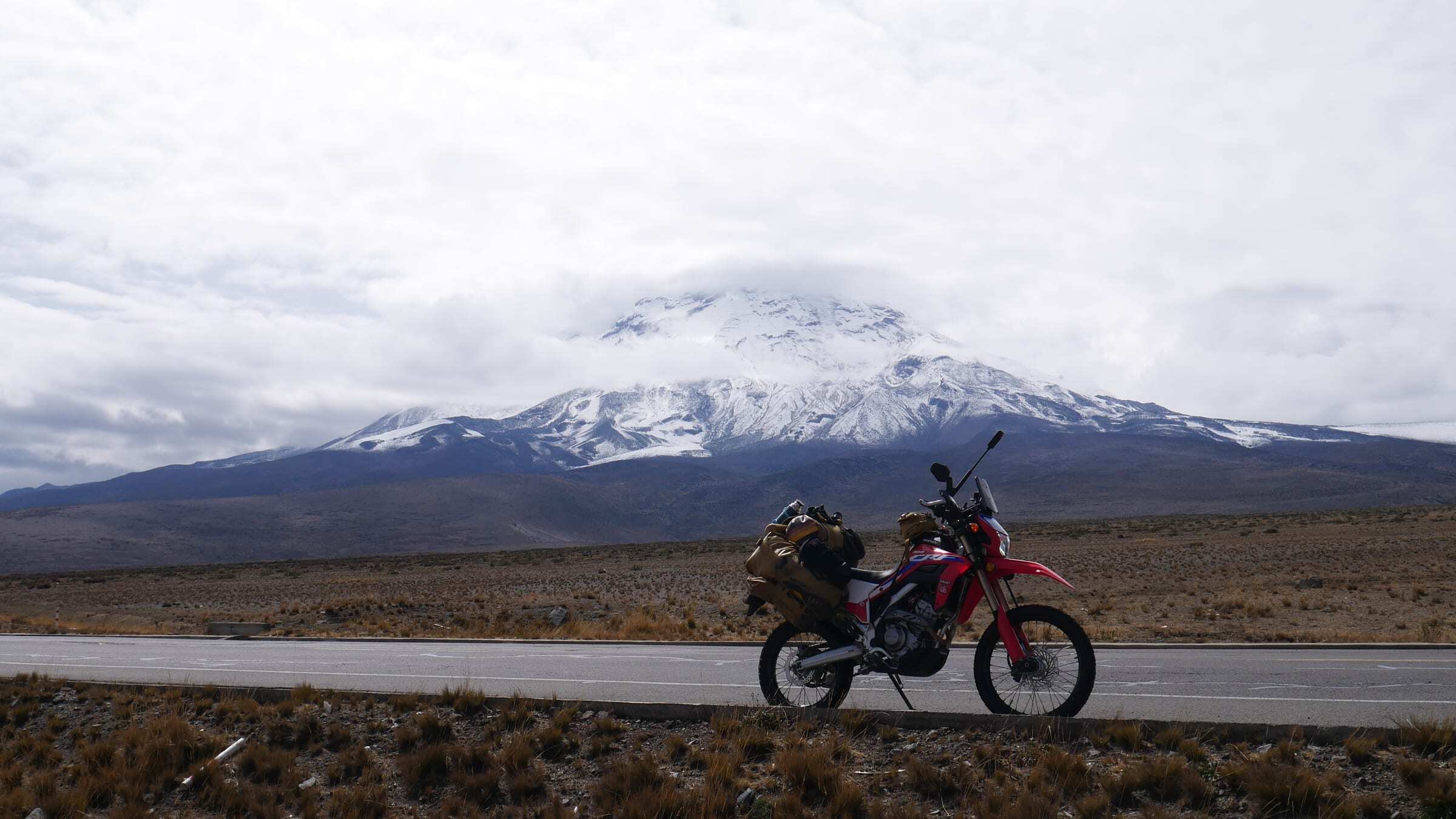 A loaded Honda CRF below the snow-covered slopes of Chimborazo, Ecuador